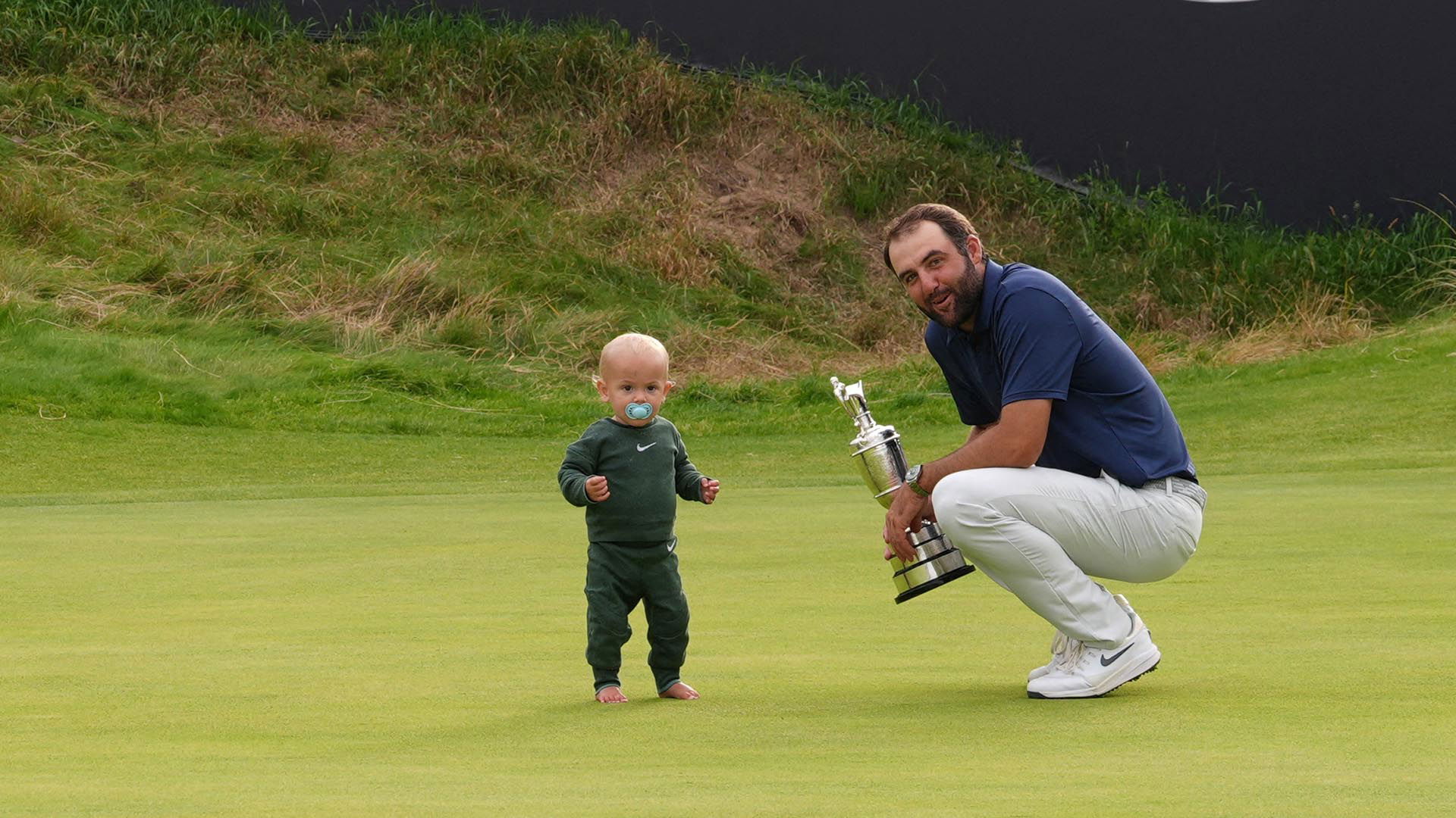Scottie Scheffler of the U.S. celebrates with his son Bennett and the Claret Jug trophy after winning The 153rd Open Championship