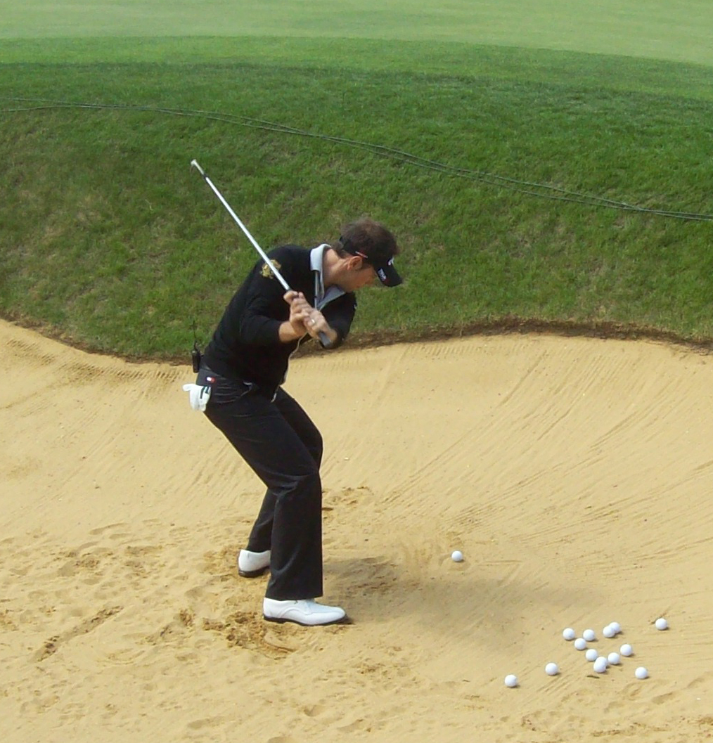 Strike the sand three inches behind the ball and hit the doughnut out of the bunker