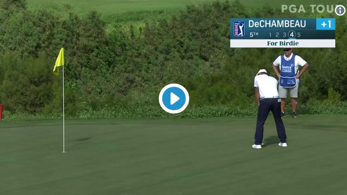 DeChambeau putting with flag in