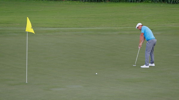 Golf course manager on golfers putting with flag in: 